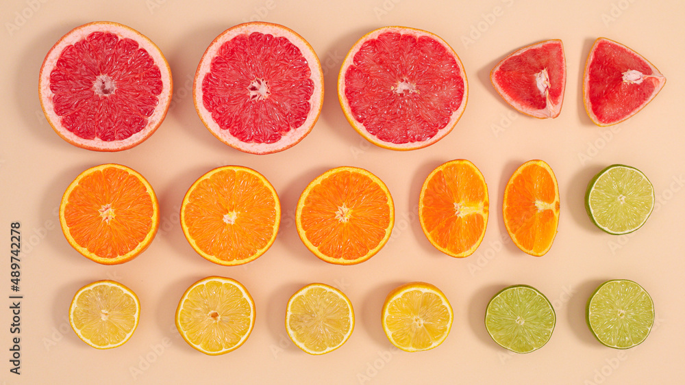 Creative layout with various citrus fruits on pastel beige background. Exotic summer food pattern Creative layout with various citrus fruits on pastel beige background. Exotic summer food pattern
