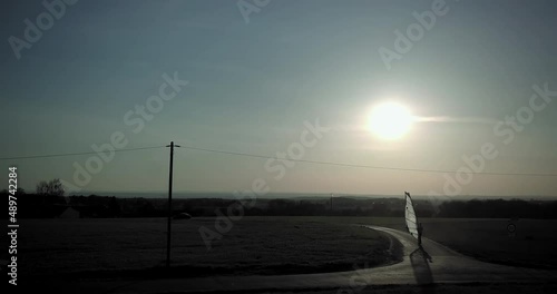 Windskating across fields. Surf sail on skateboard along a road with little wind in the sunset.