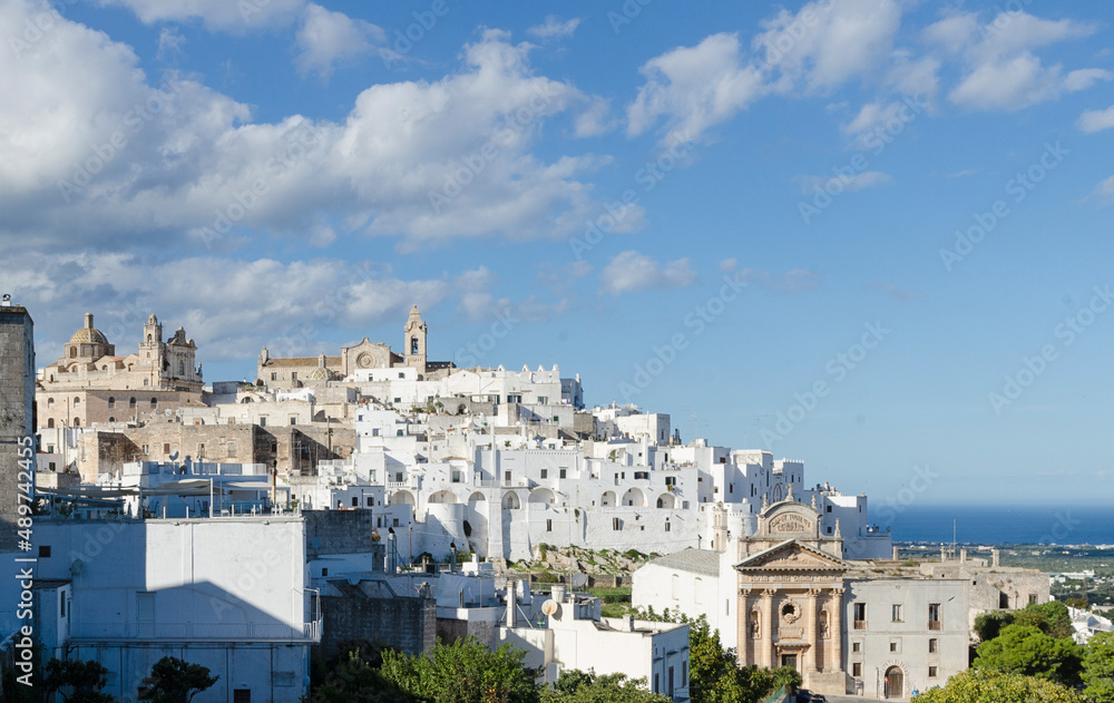 View of the town country with white building on the hill in Apulia in Italy. Landscape with blue sky. Travel in Europe. Cityscape. 