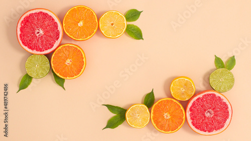 Creative layout with copy space and tropic summer citrus fruits and green natural leaves on beige background. Flat lay