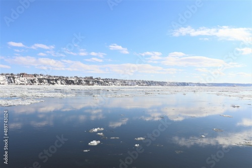 River landscape in winter. Iceberg on a river. St-Laurent river in Quebec city during the winter. Blue sky and water.  Reflection of the water.