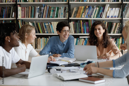 Fotografía Happy group of diverse multiracial friendly students talking, discussing new school project ideas together, enjoying preparing for examinations, doing common research in library, education concept
