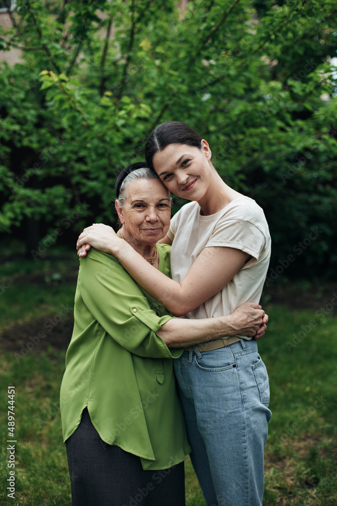 Grandmother and granddaughter hugging and smiling in the garden Grandmother and granddaughter hugging and smiling in the garden