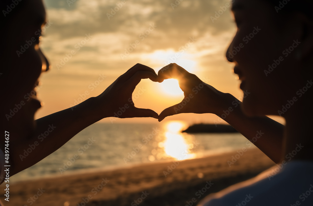 Silhouette of happy young couple forming a heart shape with their hands ...