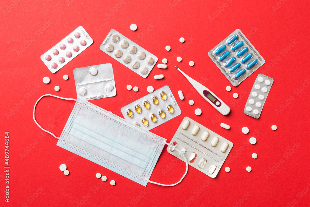 Fototapeta premium Protective face masks or surgical masks, medicine pills and thermometer on table background. Coronavirus disease. Corona virus concept. Space for text