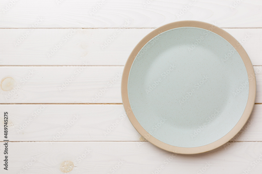 Top view of empty light plate on wooden background. Empty space for your design Top view of empty light plate on wooden background. Empty space for your design