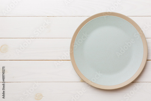 Top view of empty light plate on wooden background. Empty space for your design