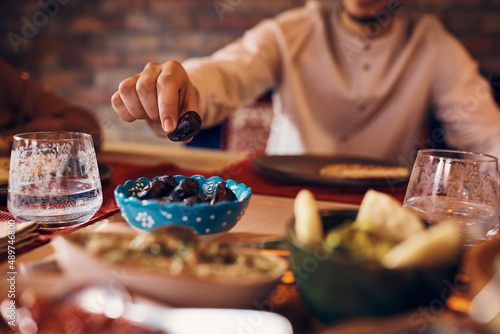 Close-up of Muslim man eats date at dining table. photo