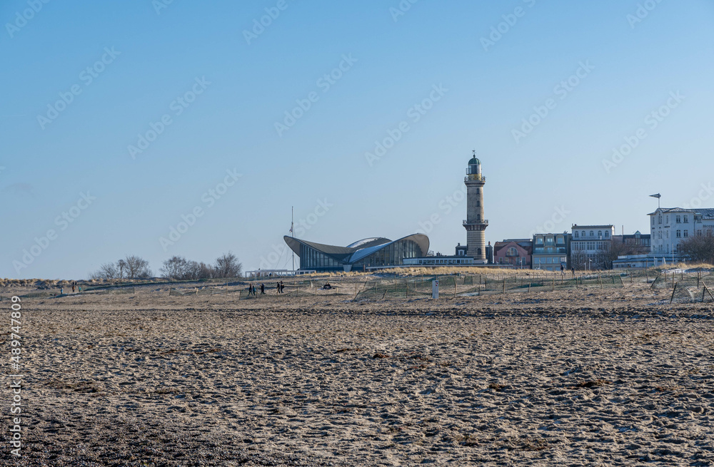 beach with lighthouse in warnemuende, germany in the background, sky with no clouds 