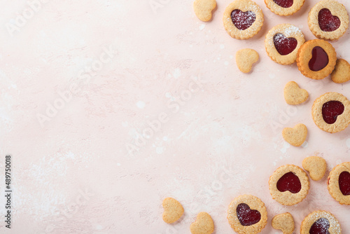 Traditional Linzer cookie with strawberry jam and powder sugar on pink beautiful background. Top view. Homemade Austrian sweet dessert food on Valentines Day. Holiday snack concept.