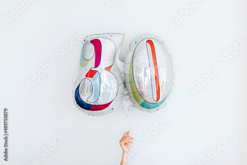 Studio shot of hand holding balloon in shape of number 30 photo