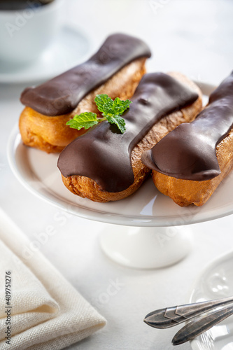 Eclairs with chocolate on white background. Delicious french sweet dessert