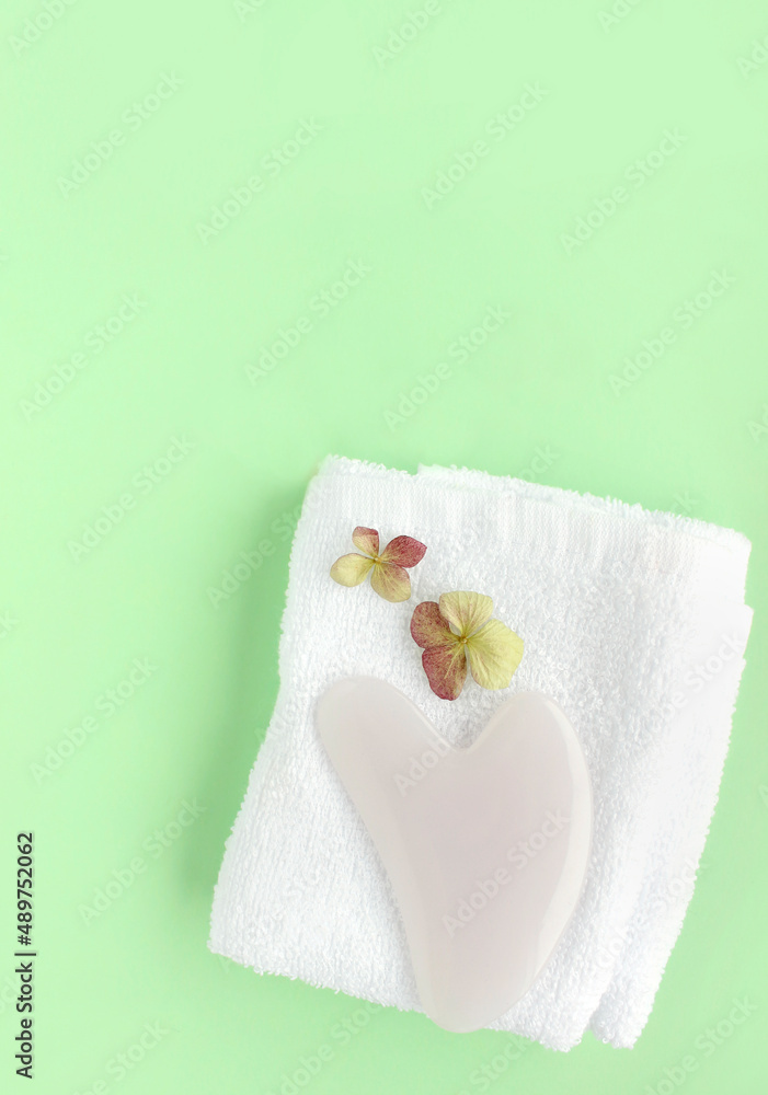 Top view of pink heart shaped guasha stone made of quartz crystal on background with copy space. Concept of alternative skin care treatment, self massage and acupressure Top view of pink heart shaped guasha stone made of quartz crystal on background with copy space. Concept of alternative skin care treatment, self massage and acupressure