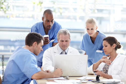 Dedicated team of healthcare professionals. A team of medical professionals working around a laptop.