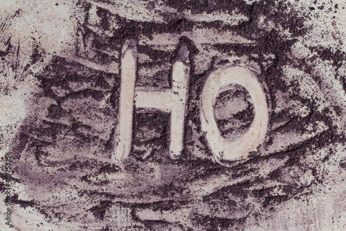 HO inscription drawn by purple color powder paint on a neutral background