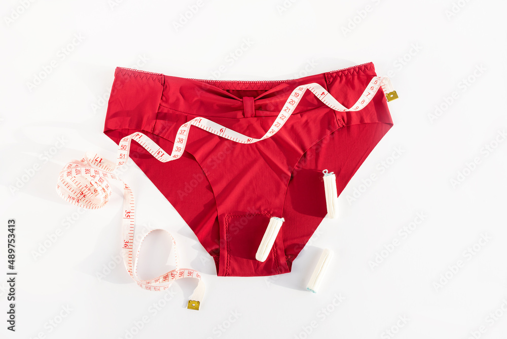 Women's underwear, tampons and metric measuring tape. Concept of