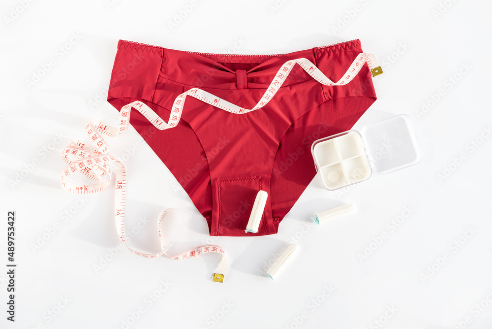 Women's underwear, tampons and metric measuring tape. Concept of