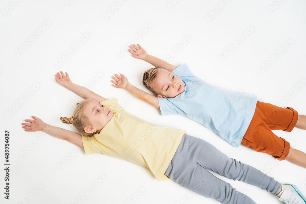 Children are lying on the floor. A boy and a girl pull the handles up. Children in sportswear. Children rest after sports.