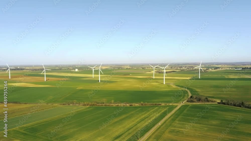Wind farm composed of many wind turbines in an area of fields in France - aerial drone view with movement to the left - green and renewable energy Wind farm composed of many wind turbines in an area of fields in France - aerial drone view with movement to the left - green and renewable energy