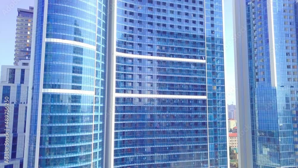 facade of a modern office building is removed from drone. close-up. drone rises and falls next to mirrored windows and balconies. Close-up shooting of the building. Real estate and architecture.