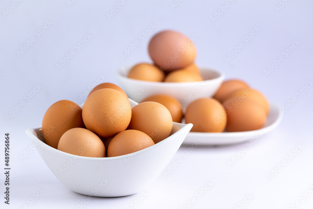 Fresh eggs stacked in white bowl and plate Fresh eggs stacked in white bowl and plate