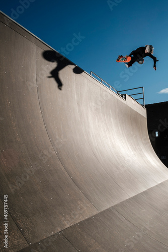 Boy doing backside air on a vert ramp and blue sky