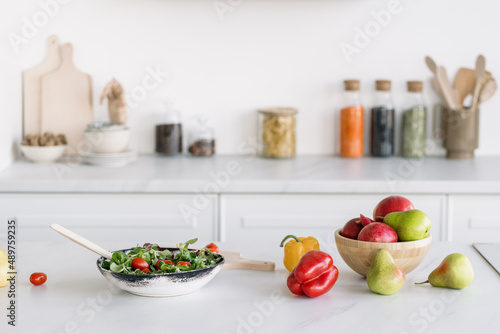 Preparing healthy salad in white modern kitchen