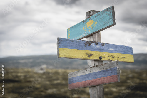 kazahkstan, ukraine and russian flags on signpost outdoors in nature.