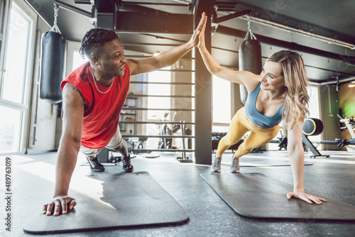 Fit man and woman in gym exercising abs with high-five