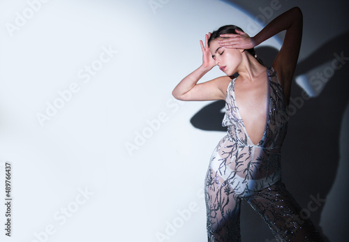 High fashion portrait of young elegant woman in studio. Fashion model, beautiful young woman posing with vogue dress, studio shot.