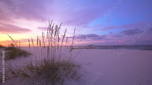 Colorful ocean sunrise with silhouetted person distantly walking the sandy beach as birds fly over the sky 