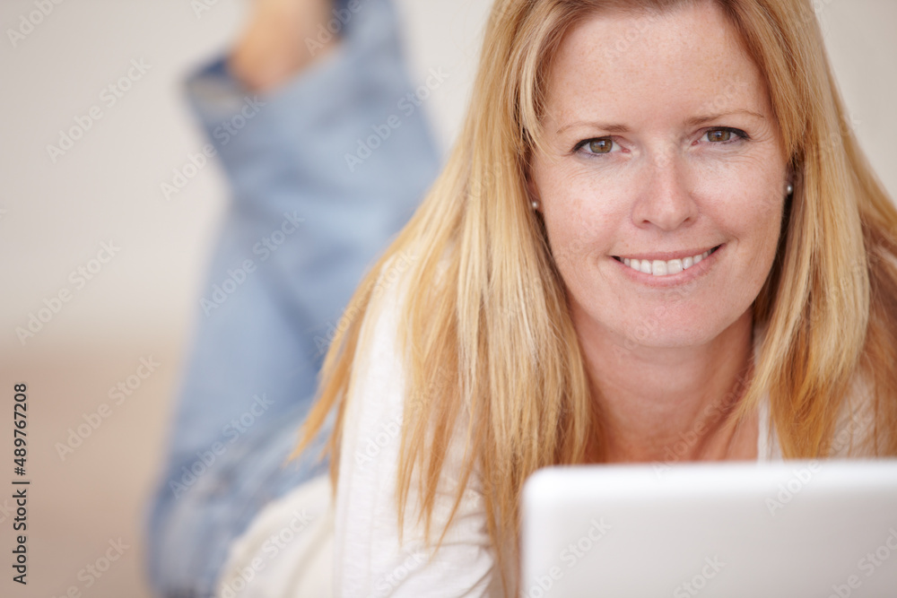Reading a book online. A beautiful mature woman working on her laptop while lying on the floor. Reading a book online. A beautiful mature woman working on her laptop while lying on the floor.