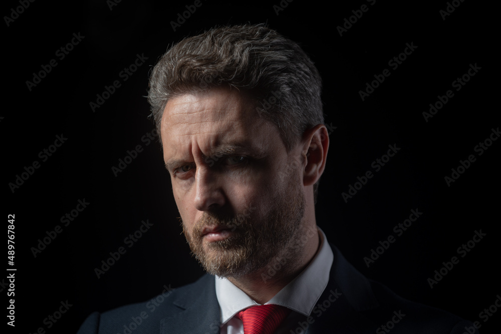 Portrait shot of a middle aged businessman in suit at dark black background. Mature business man thinking, closeup face. Portrait shot of a middle aged businessman in suit at dark black background. Mature business man thinking, closeup face.