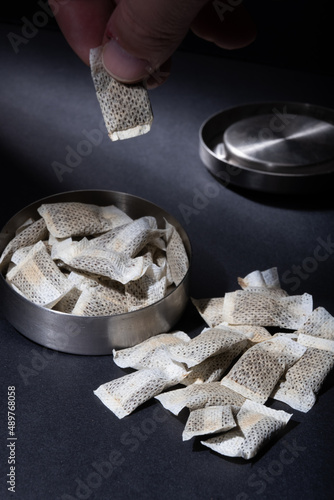 Closeup of metallic Swedish snus can with white portions of smokeless tobacco pouches against a dark background.