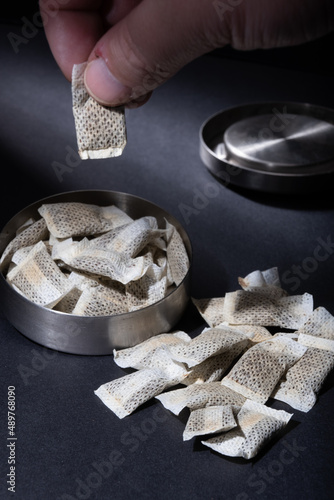 Closeup of metallic Swedish snus can with white portions of smokeless tobacco pouches against a dark background.