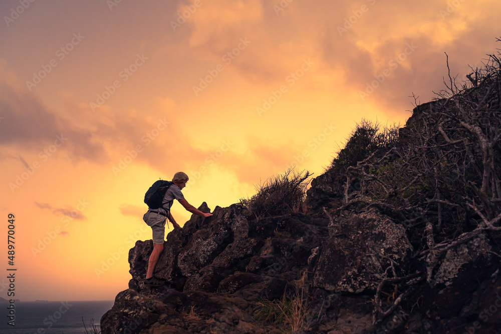 Man climbing up the edge of a steep mountain cliff 