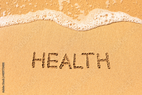 Word health written on sandy beach background 