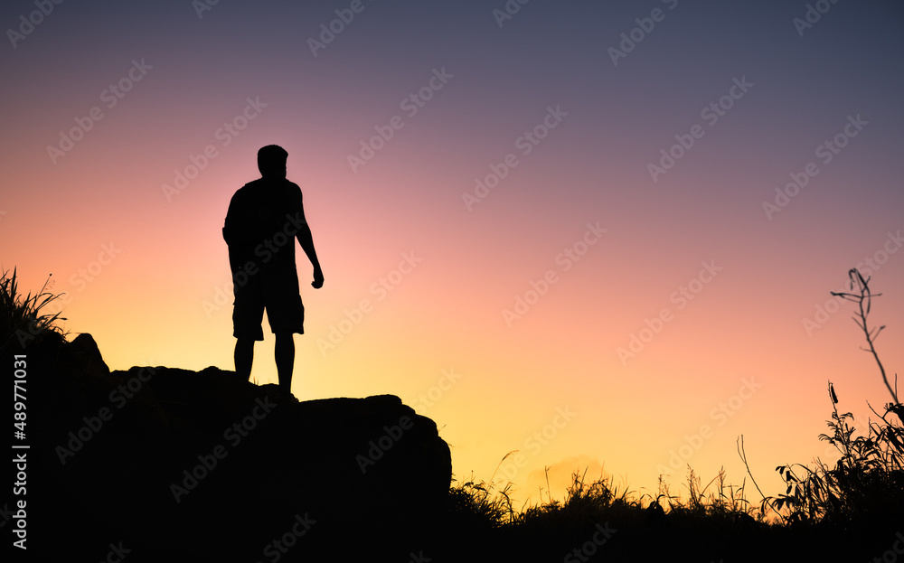 Man standing on a mountain facing the sunrise