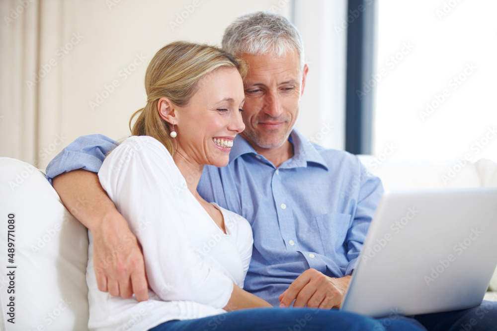 Where would you like to go for our anniversary. A young married couple sitting together on the sofa with their laptop. Where would you like to go for our anniversary. A young married couple sitting together on the sofa with their laptop.