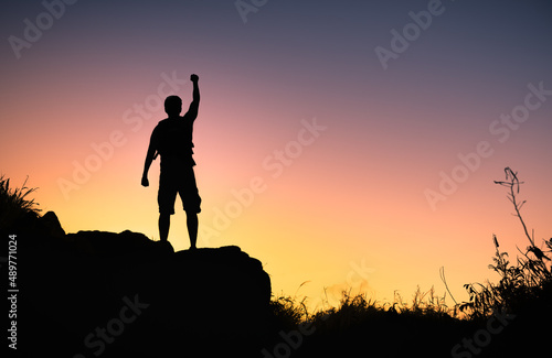 silhouette of a person on the top of mountain with fist in the air. Winning   goal setting  and courage concept. 