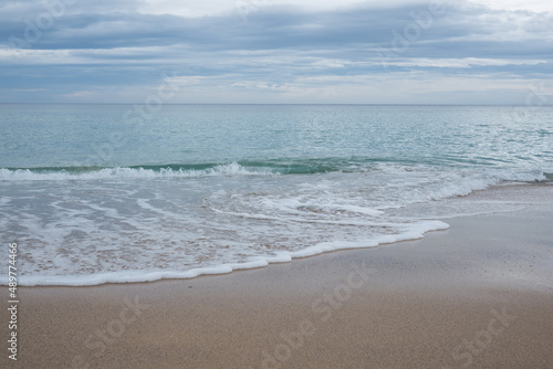 Australian south coast beach. Water and sea foam on sand.