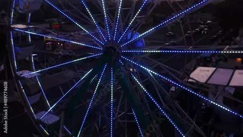 Outdoor carnival event with ferris wheel turning and other amusement and thrill rides moving on main street fair grounds.  Sunset event, shows, and party in a small country town. Tickets for passenger
