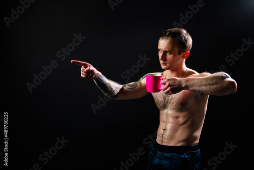 Man on black background keeps dumbbells pumped up in fitness torso, training strong healthy Lift handsome metal, guy fit In the athlete's pink cup he smiles
