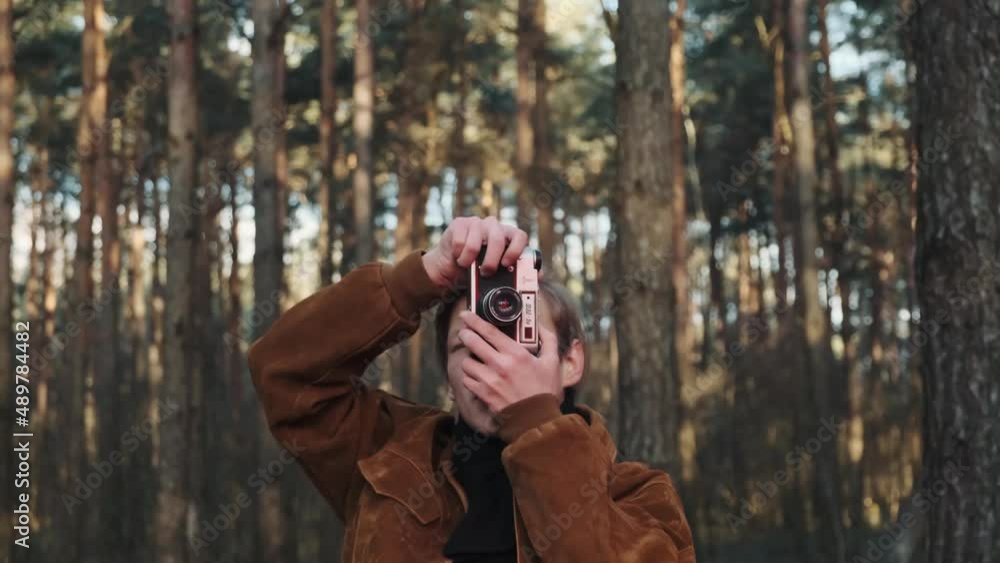 A young blond male photographer takes pictures of nature. Photographer takes pictures in the woods with a retro camera. Young photographer dressed in retro style. . High quality 4k footage A young blond male photographer takes pictures of nature. Photographer takes pictures in the woods with a retro camera. Young photographer dressed in retro style. . High quality 4k footage