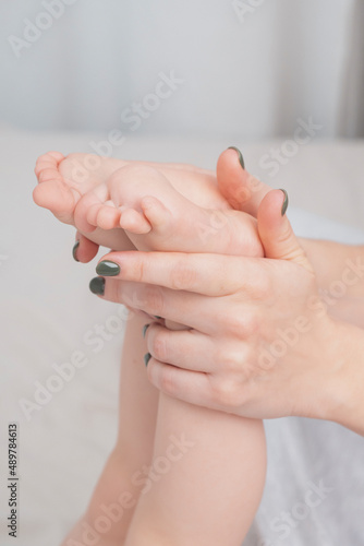 Baby s small legs in mom s hands  close-up. The concept of family happiness  loving parents. Baby care  massage. Background for Mother s day  baby s day. Touching mother and child