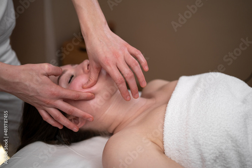 Young attractive pretty brunette gets a facial massage at the spa. The concept of a healthy lifestyle and body care.