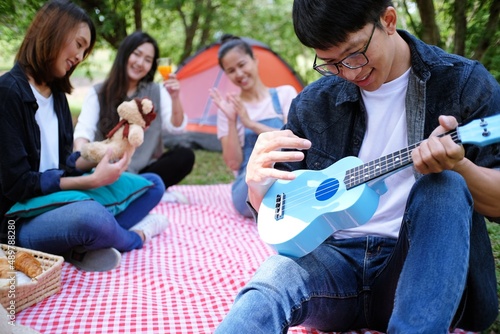 Happy friends picnic, Man playing a guitar having fun outdoor.