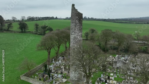 Monasterboice, County Louth, Ireland, January 2022. Drone gradually orbits the ruined Round Tower with surrounding monastic cemetery from the west side ascending to reveal its missing conical cap. photo