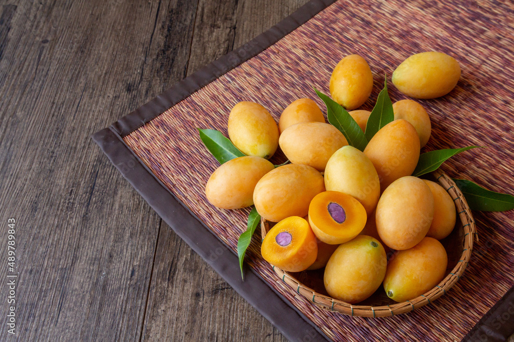 bunch of marian plum in a basket on wooden table with copy space
