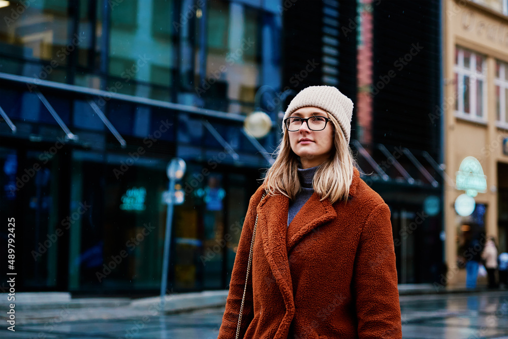 Woman in coat and eyeglasses walking at city street at rainy day Woman in coat and eyeglasses walking at city street at rainy day
